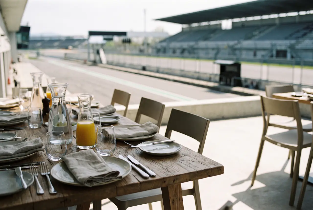 Set tables on a sunny terrace beside a race circuit straight and grandstand